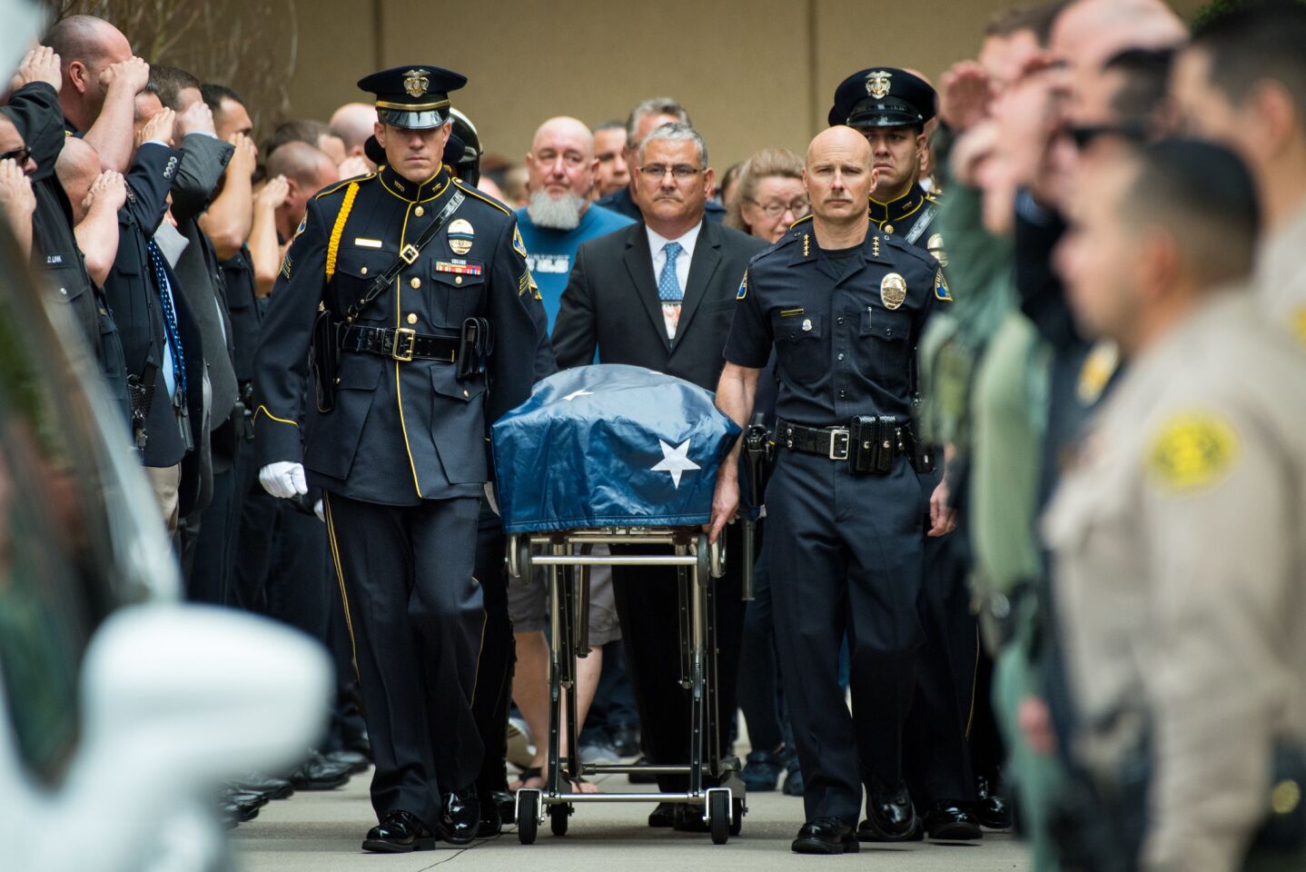 Whittier Police Chief Jeff Piper, right, and other law enforcement personnel escort the body of a slain Whittier police officer from UC Irvine Medical Center.