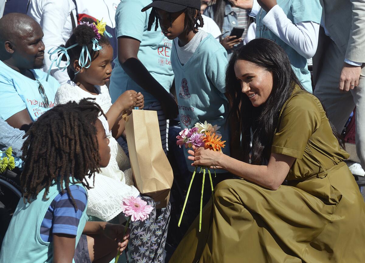 The former Meghan Markle accepts flowers from a child