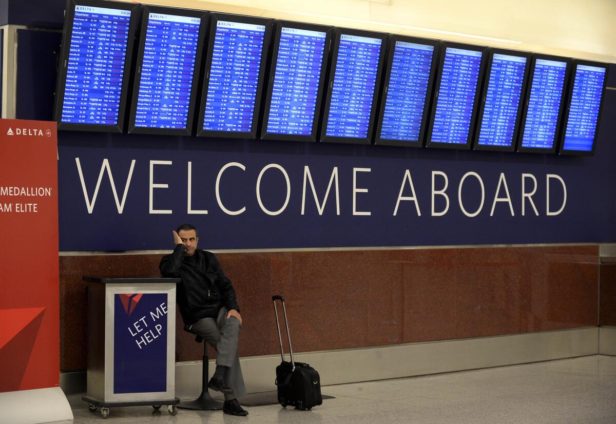 An airline passenger waiting for his rescheduled flight to Orlando, Fla., under the departure board at Hartsfield-Jackson International Airport in Atlanta. Domestic air fares for this summer should remain flat compared to 2014, according to new data.