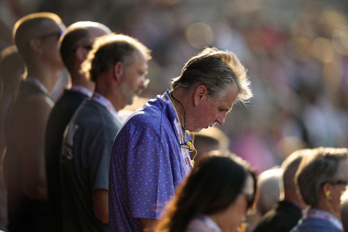 Fans bow their heads during a prayer for former President Trump before an IndyCar auto race Saturday at Iowa Speedway.