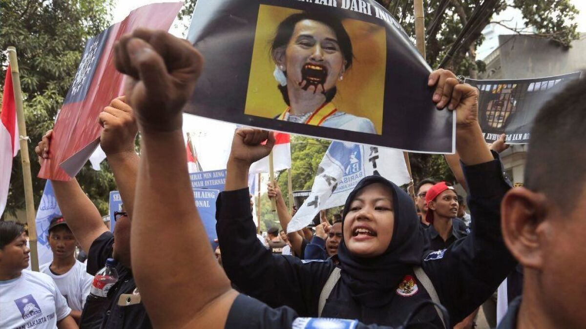A Muslim woman shouts slogans while holding a defaced portrait of Myanmar's leader Aung San Suu Kyi during a rally outside Myanmar's Embassy in Jakarta, Indonesia.