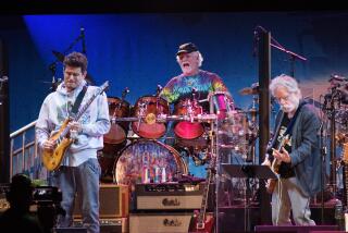  John Mayer on guitar, Bill Kreutzmann on drums and Bob Weir on guitar of Dead and Company playing on a stage