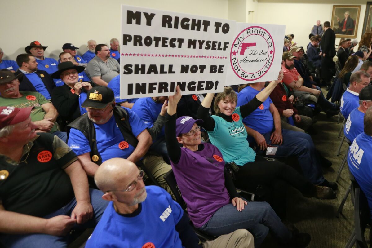 Gun rights protesters hold signs prior to the start of a meeting of the Senate Judiciary committee at the Capitol in Richmond, Va. 
