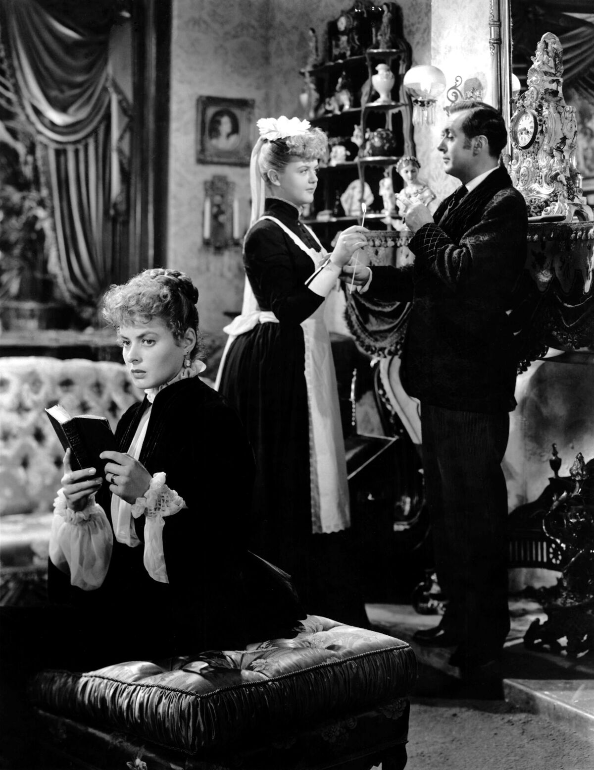 Ingrid Bergman, left, reads a book while Angela Lansbury and Charles Boyer are standing behind in "Gaslight" (1944)