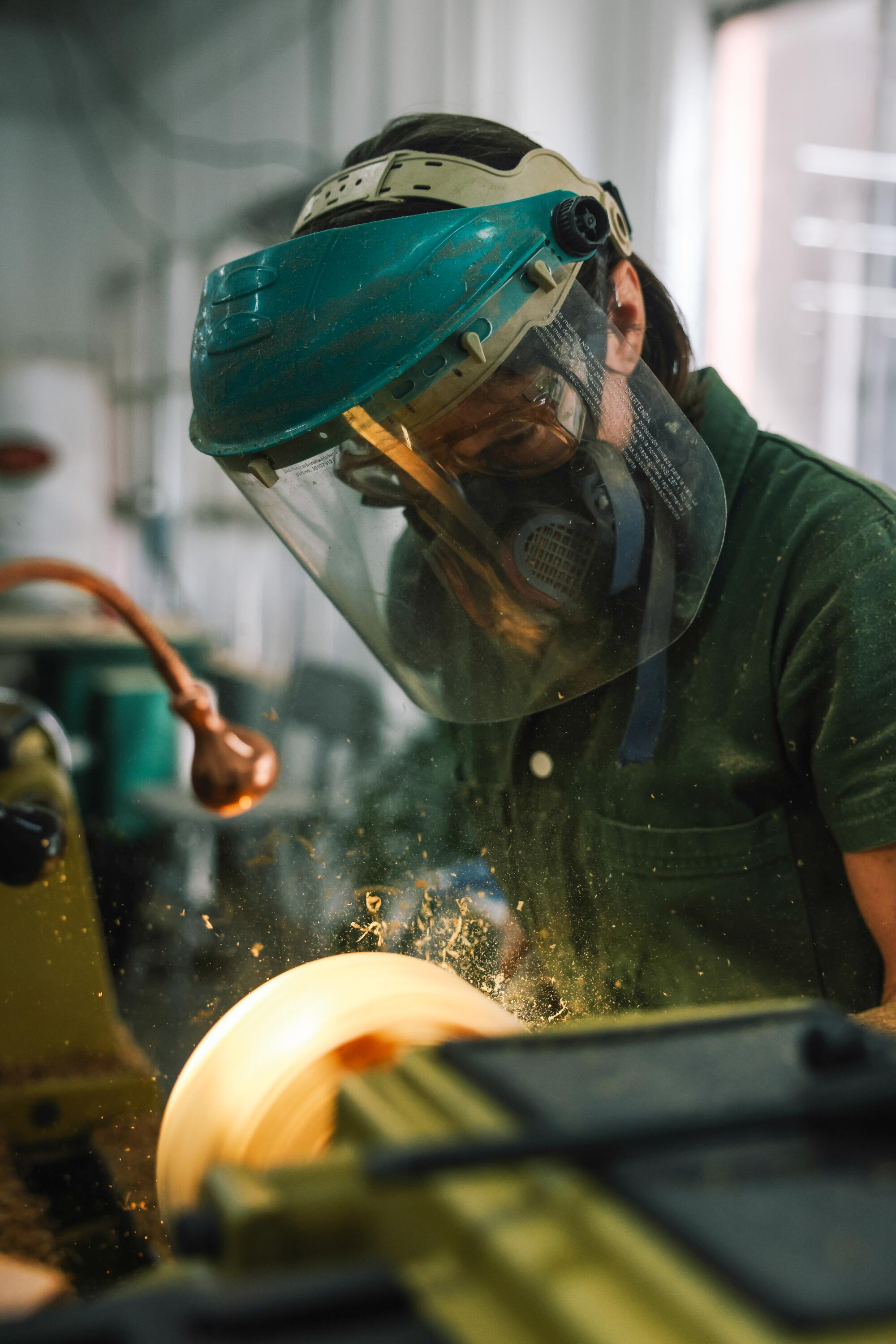 a woman wears a clear face shield while woodworking