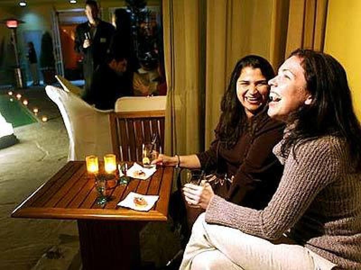 Sunana Batra, left, and Michelle Blake enjoy the scene at the Mosaics pool area, which offers cabanas, hurricane candles and heat lamps.