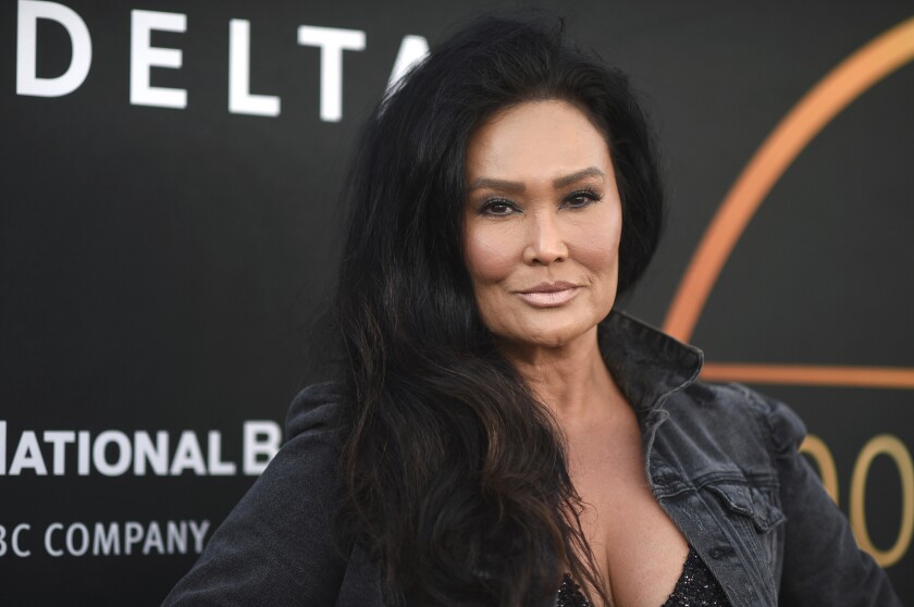 A woman with long dark hair in a black jacket on a red carpet