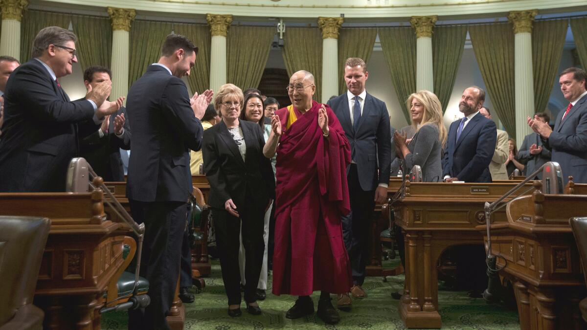 The Dalai Lama is escorted by state lawmakers through the California Assembly chamber.