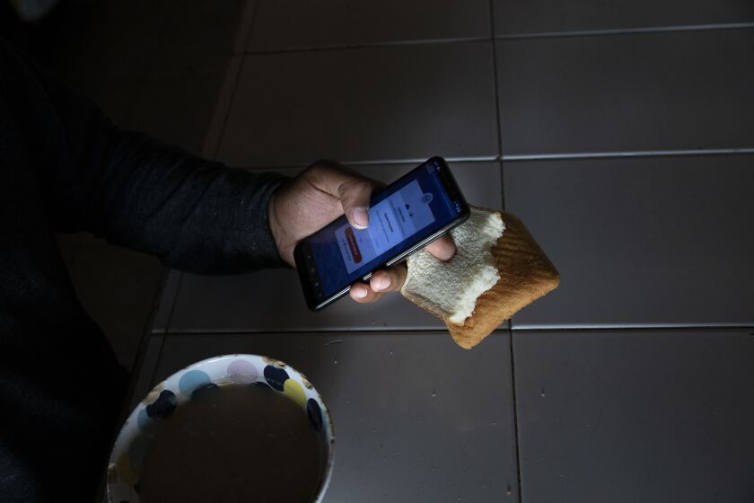 Tijuana , Baja California - May 11: Ronald, 21, of Venezuela, eats breakfast while trying to figure out changes made in the CBP One smartphone app at Espacio Migrante on Thursday, May 11, 2023 in Tijuana , Baja California. Ronald was persecuted b based on sexual orientation. Title 42 was put in place by the Trump administration in March 2020 based on a public health order that was used to block migrants from entering the United States. The policy is expected to end at 11:59 p.m. Thursday. (Ana Ramirez / The San Diego Union-Tribune)