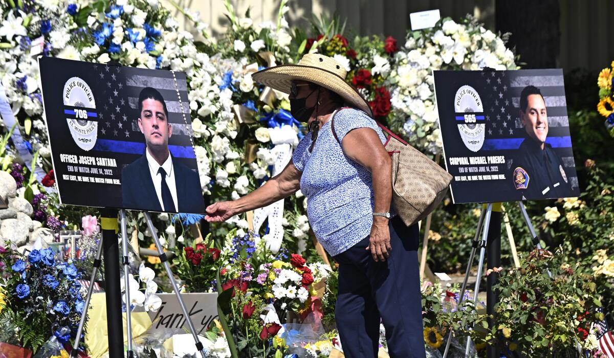 FILE - A woman touches a picture of officer Joseph Santana at a makeshift memorial outside the El Monte City Hall and police station on June 15, 2022, in El Monte, Calif. Pictured, at right, is fellow police officer Michael Paredes. Mourners attended a funeral, Thursday, June 30, 2022, for the two Southern California police officers slain earlier this month. (Keith Birmingham/The Orange County Register via AP, File)
