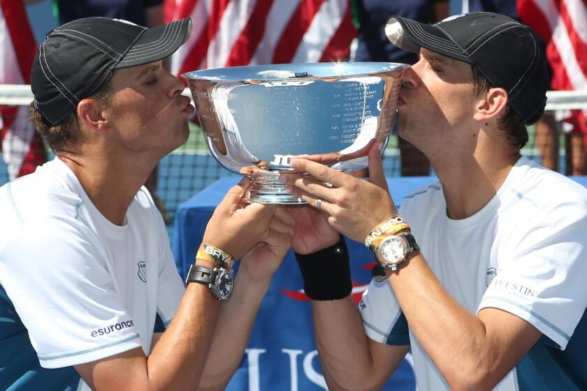 Bob, left, and Mike Bryan kiss the men's doubles championship trophy after defeating Marc Lopez and Marcel Granollers at the U.S. Open on Sunday.