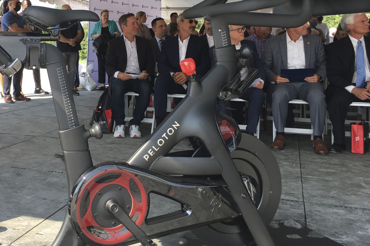 FILE - Peloton CEO John Foley, left, is seen behind one of his company's fitness machine along with others gathered for the groundbreaking for the company's first U.S. factory, Monday, Aug. 9, 2021, in Luckey, Ohio. Investors bailed on Peloton, Friday, Nov. 5, after the company said it expected to lose more money than previously forecast in 2022 as the pandemic winds down and fewer people feel compelled to buy high-end exercise equipment for their homes. (AP Photo/John Seewer, File, File)