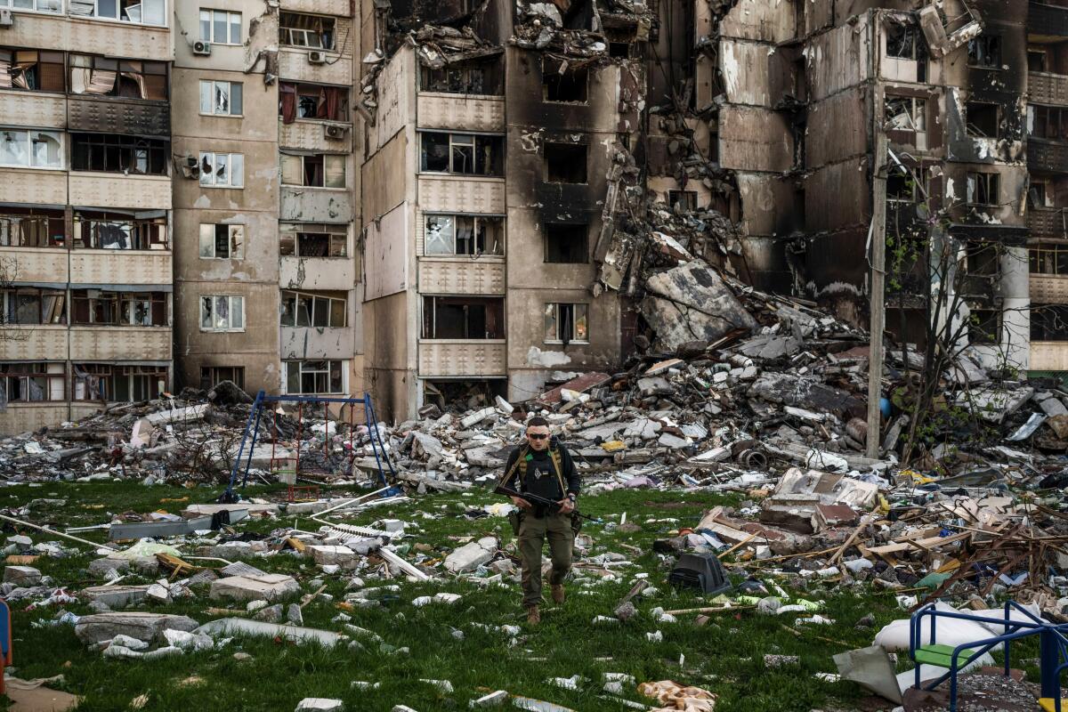 Ukrainian soldier walks amid the rubble of a building.