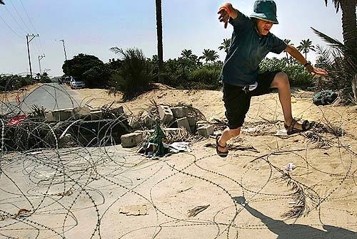 A protester jumps over barbed wire after dousing debris blocking the main road into Shirat Hayam with lighter fluid. Despite fierce resistance, Israeli soldiers removed settlers as well as protesters from the settlement Thursday.