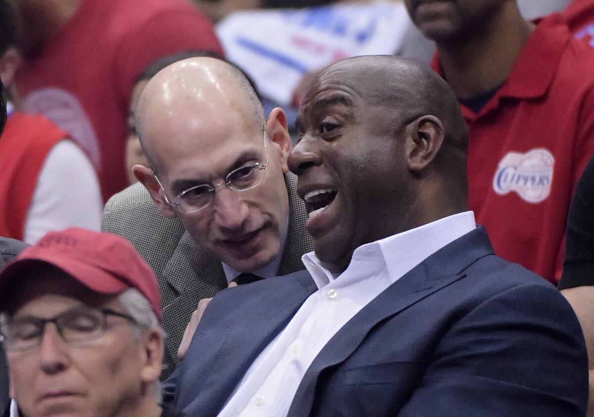NBA Commissioner Adam Silver, left, talks with Magic Johnson as they watch a Clippers-Thunder game in 2014.
