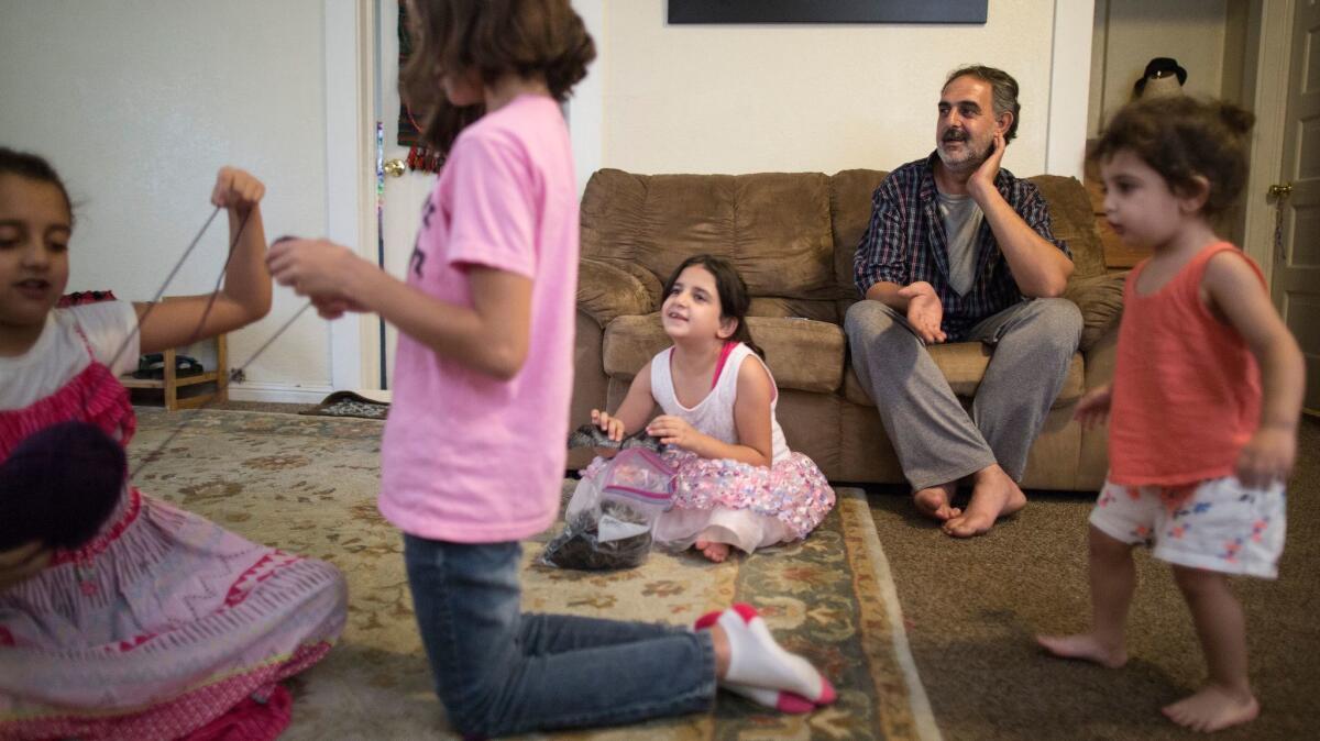 Syrian refugee Taiseer Al Souki, right, relaxes at home with his family in Fresno.
