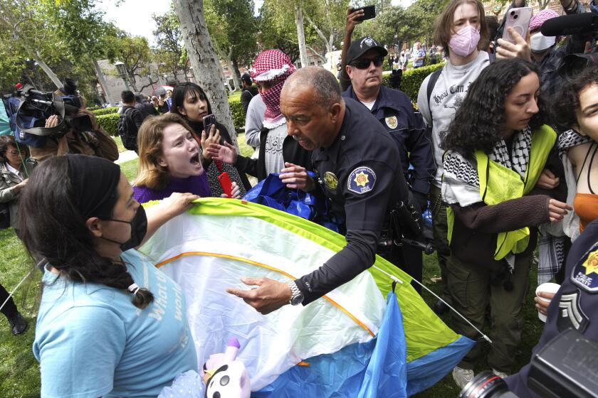 Manifestantes de la Universidad del Sur de California discuten con agentes de seguridad pública de la universidad mientras intentan retirar tiendas de campaña en el Parque de los Exalumnos durante una protesta en favor de los palestinos, el miércoles 24 de abril de 2024, en Los Ángeles. (AP Foto/Richard Vogel)