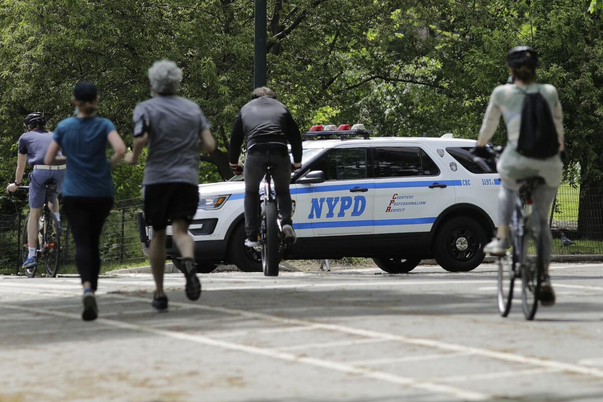 Runners and cyclists pass a New York police vehicle in Central Park on Saturday. 