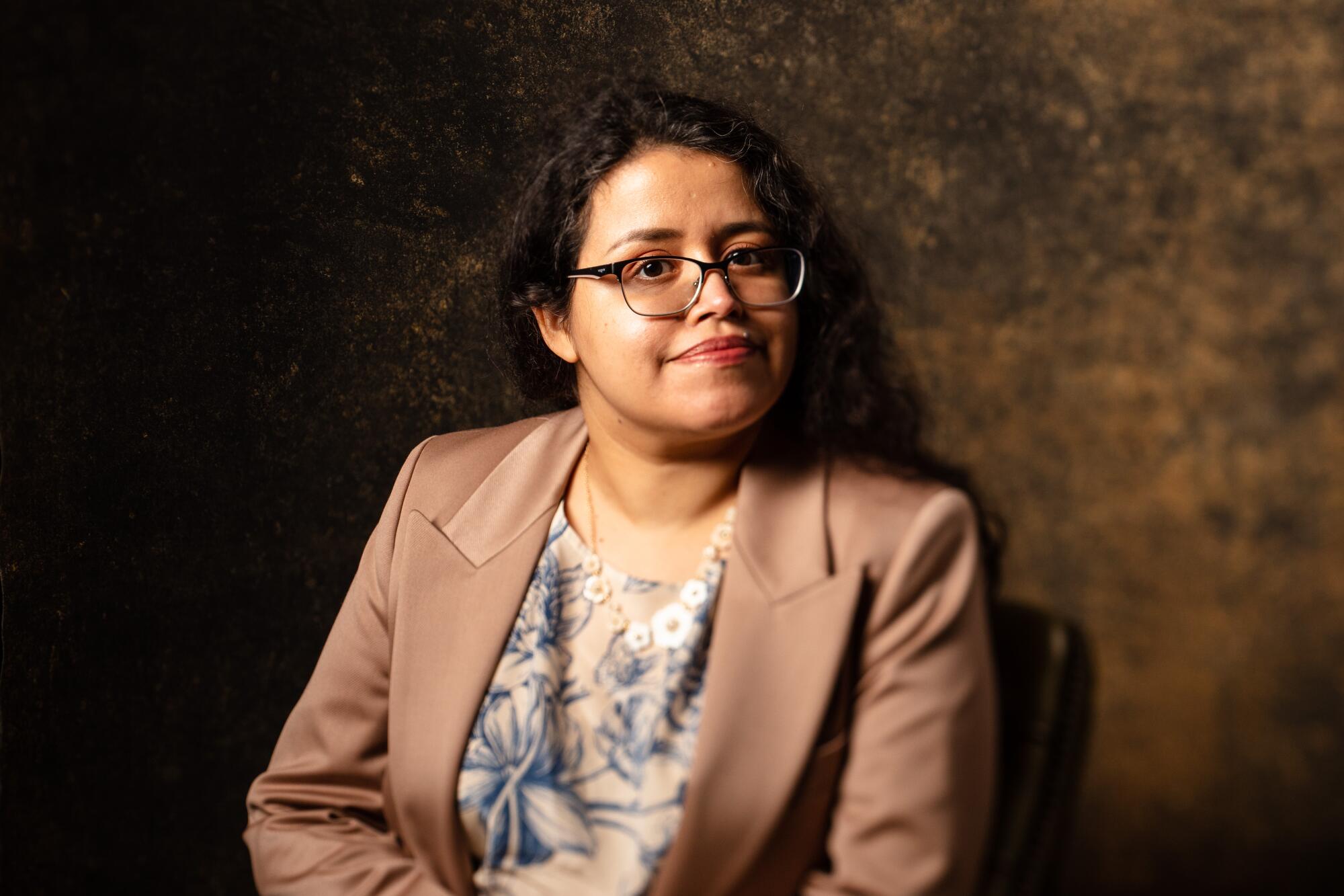 A woman in a blouse and blazer at a desk 