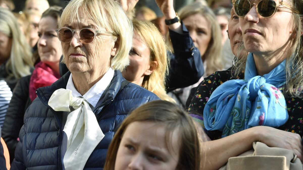 Women wear bows around their necks in a show of solidarity during a rally outside the Swedish Academy in Stockholm to demand that the members of the board that awards the Nobel Prize in Literature resign.