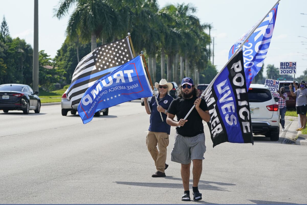Trump supporters wave flags in front of a small group of Biden backers in Miramar, Fla. 