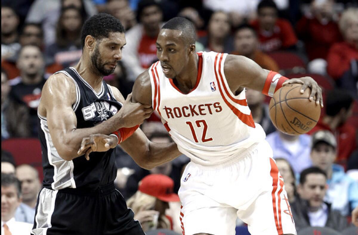 Rockets center Dwight Howard tries to power his way past Spurs power forward Tim Duncan during a game last month in Houston.