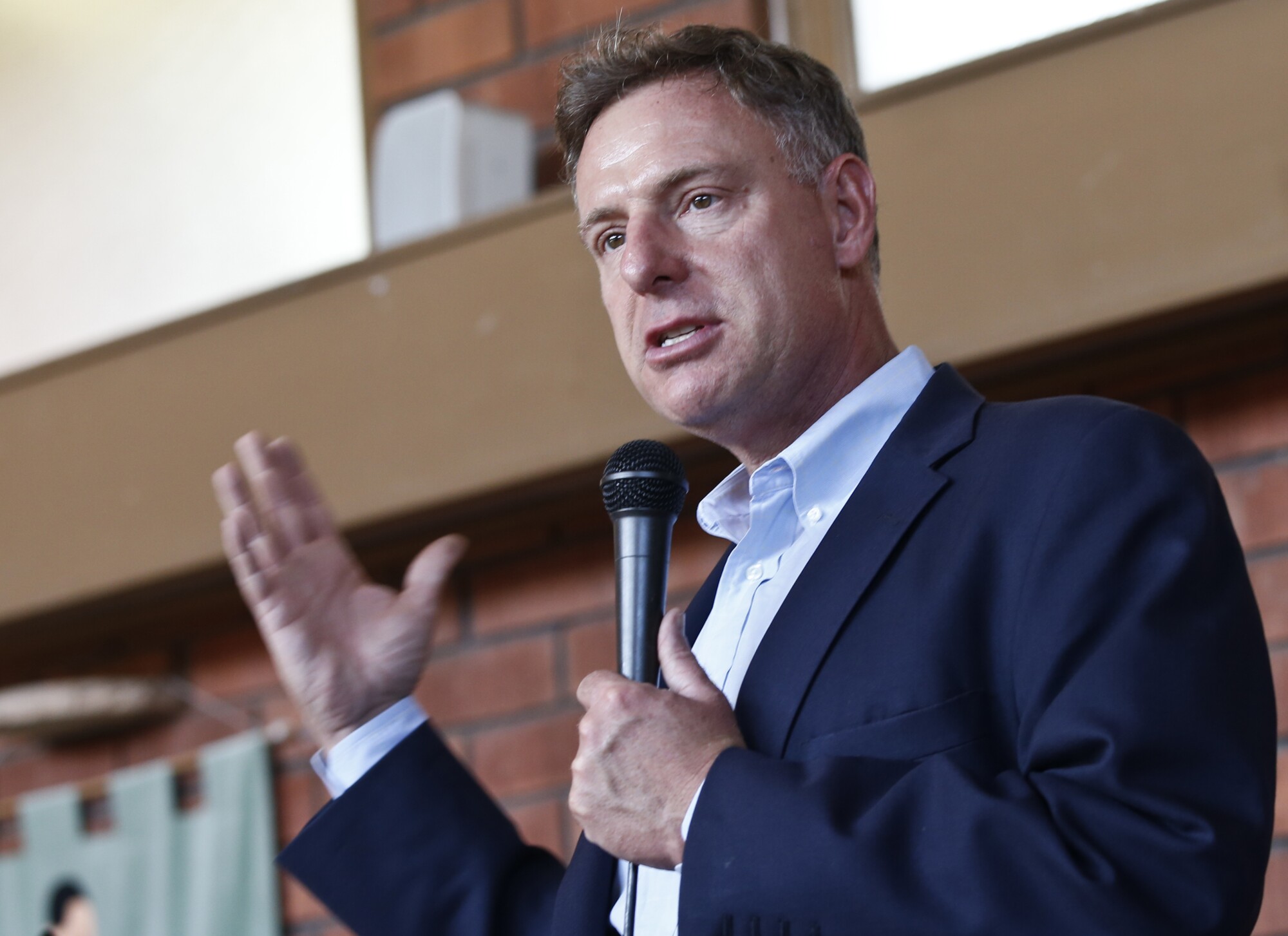 Representative Scott Peters gestures as he speaks into a microphone.