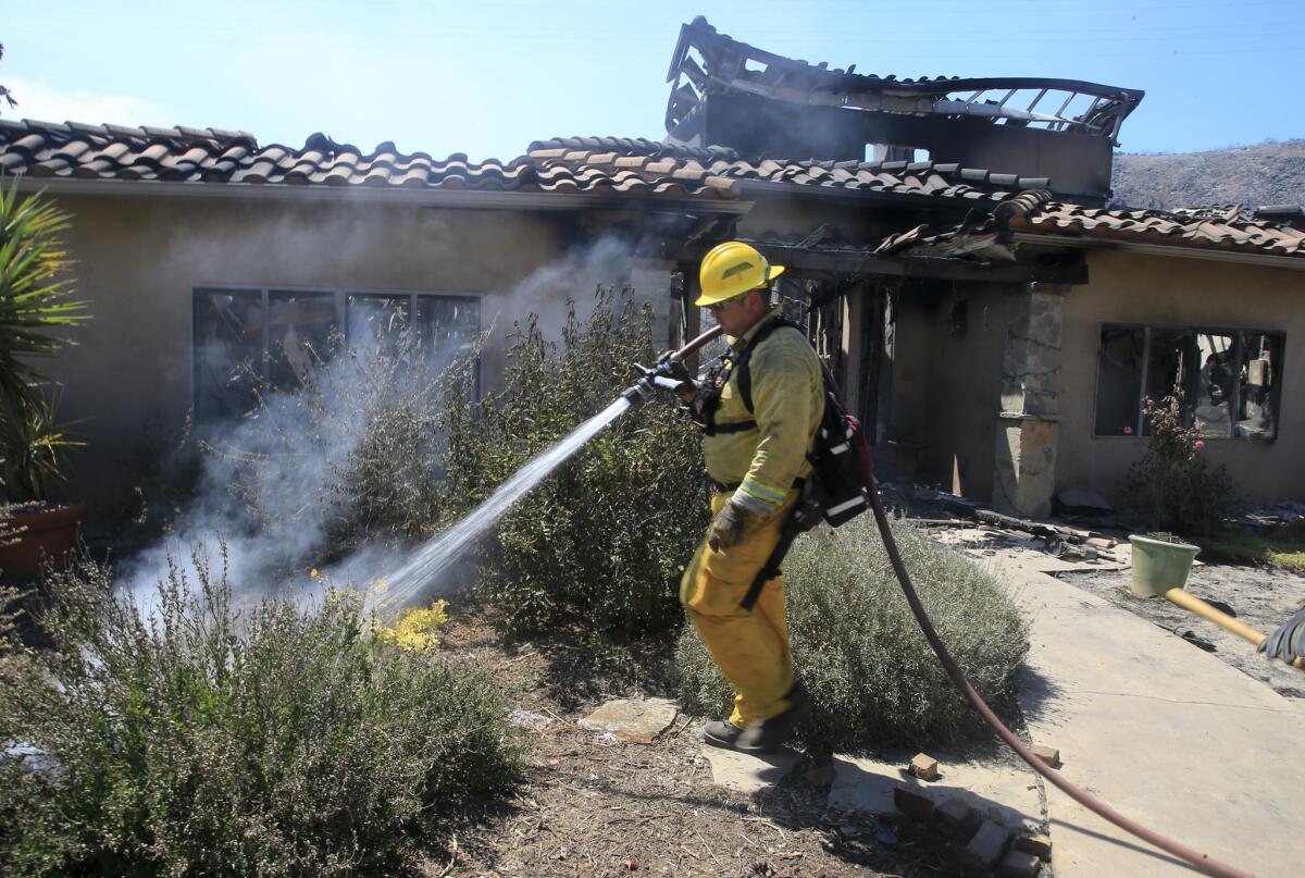 Firefighters from San Bernardino County douse hot spots at a home in Escondido last month.
