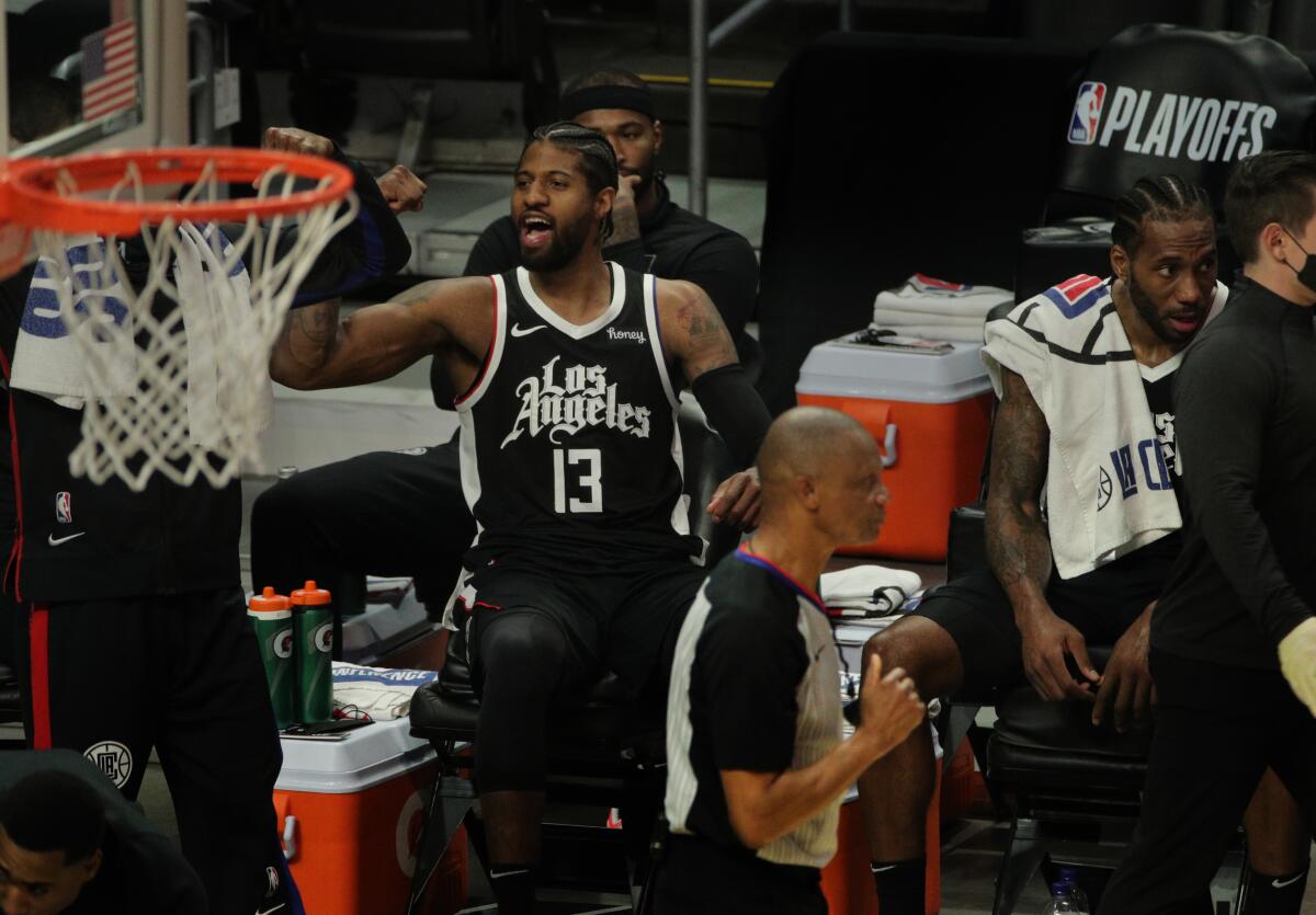 The Clippers' Paul George (13), seated next to Kawhi Leonard, cheers toward the end of the win over Utah on June 12, 2021. 