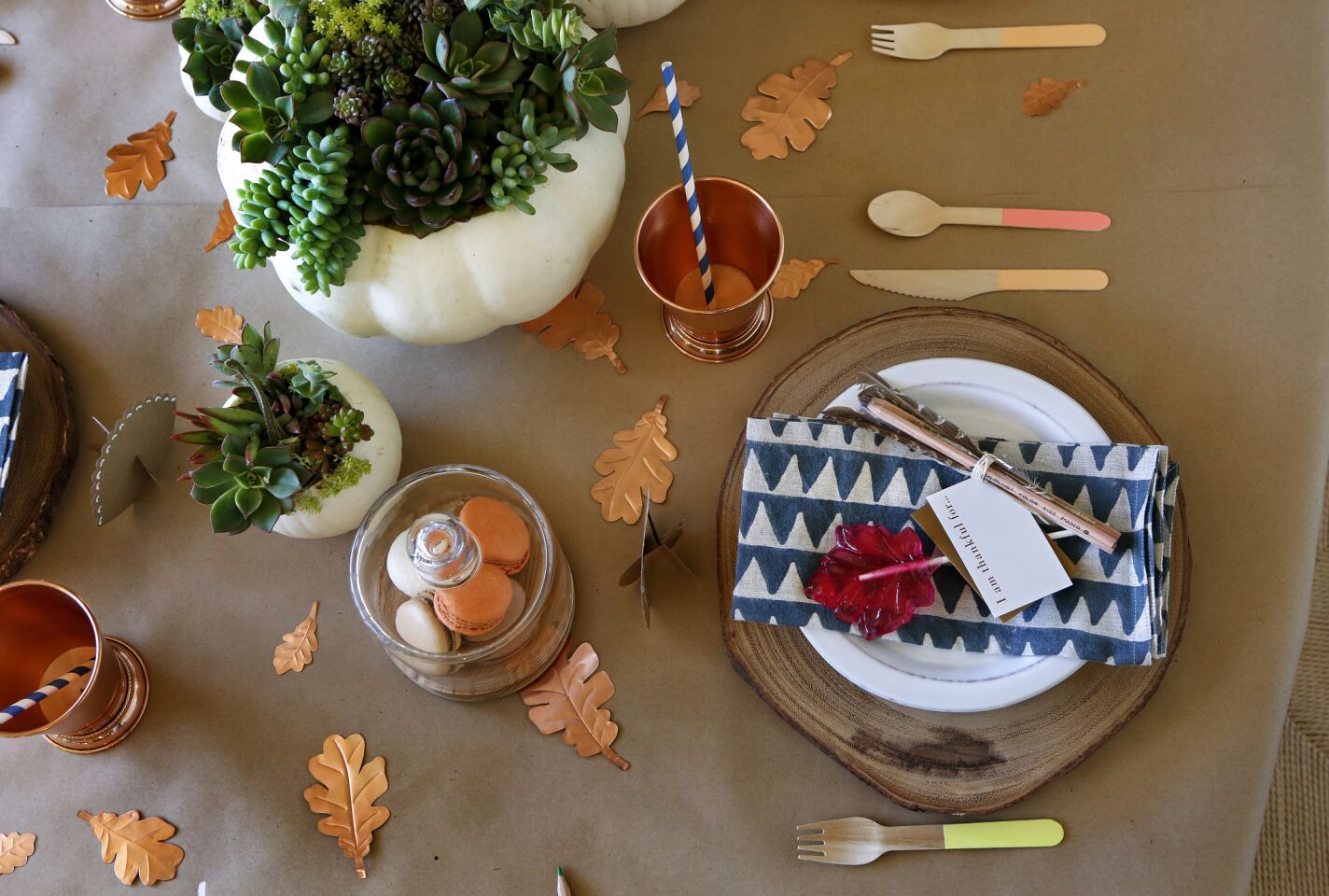 Wooden, disposable utensils, copper leaves, and a lollipop on the place setting are part of a kid's tablescape for the holidays, arranged by Shannon Wollack, David Ko, and Julianne Goldmark, designers with Studio Life.Style.
