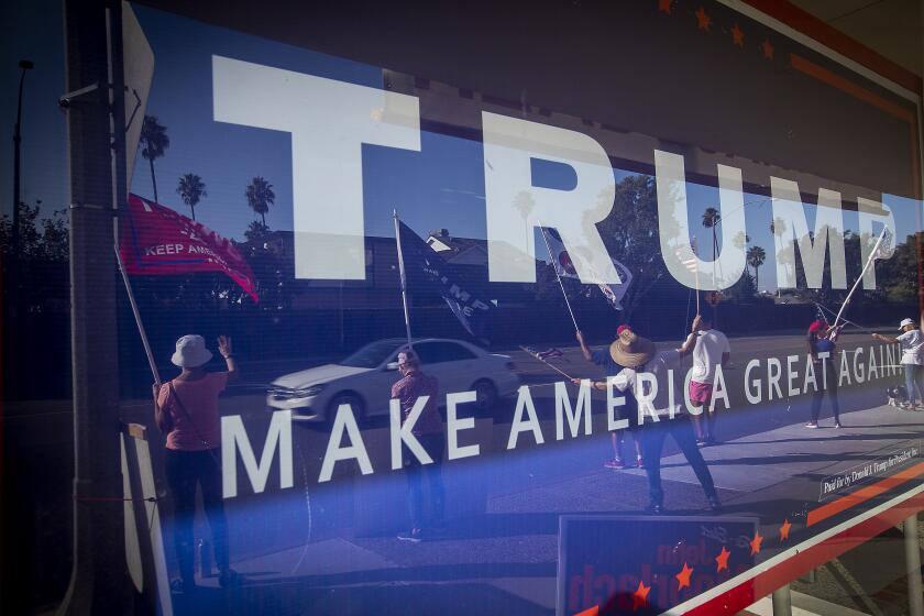 NEWPORT BEACH, CA - NOVEMBER 03: Pres. Trump supporters are reflected in a Republican Party headquarters window as they cheer on passing motorists on election day Tuesday, Nov. 3, 2020 in Newport Beach. (Allen J. Schaben / Los Angeles Times)