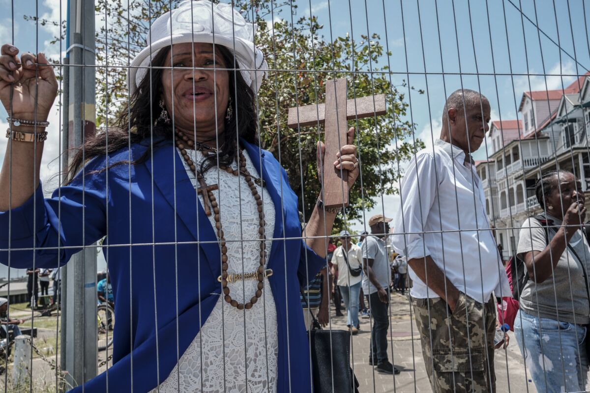 Kite Esajas sostiene un crucifijo durante una manifestación antigubernamental en Paramaribo, Surinam, el viernes 24 de marzo de 2023. (AP Foto/Steve Tjin)