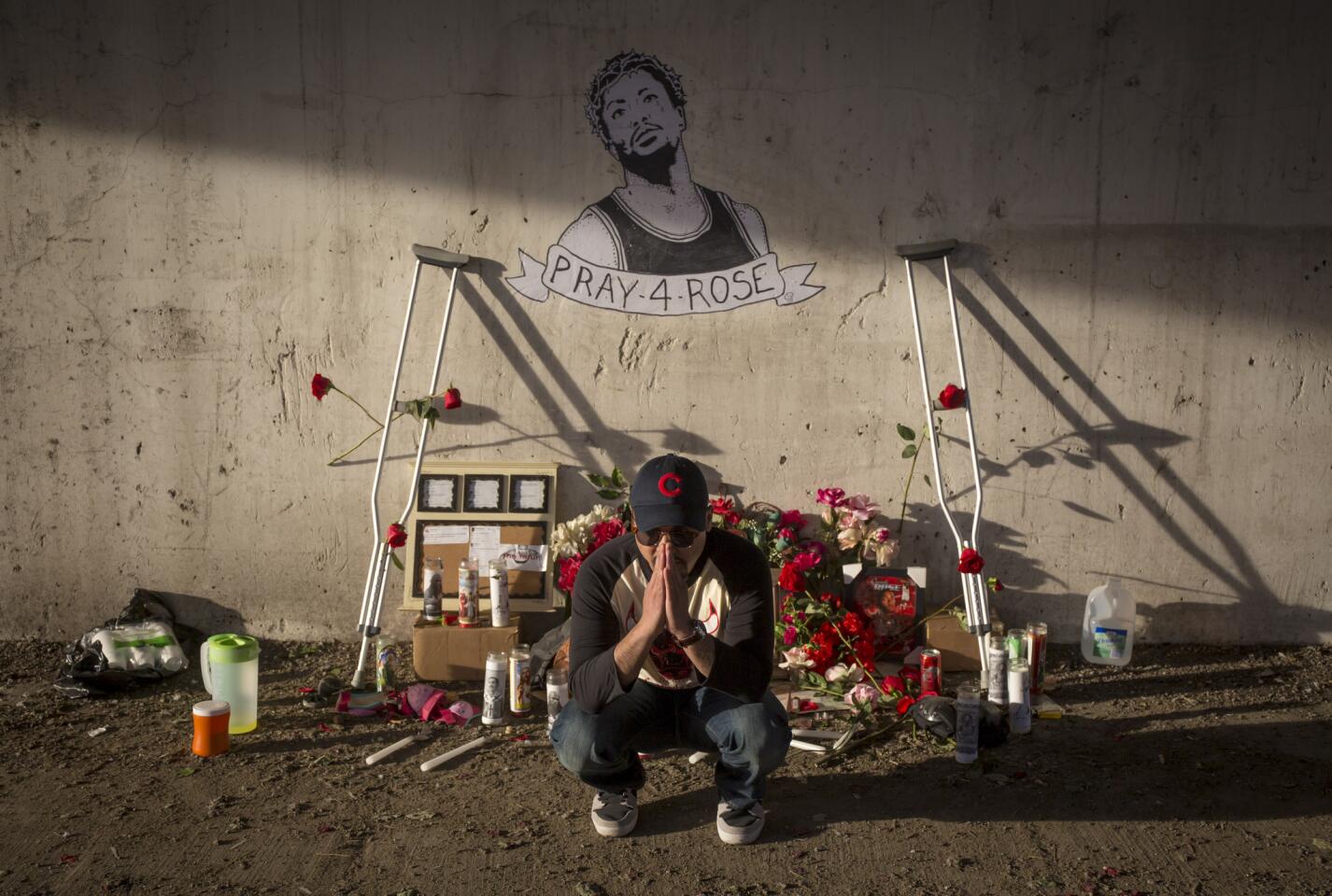 Gary Phanhdone, a fan from Denver on his way to tonight's Bulls game, poses for a friend's photo at a shrine to the injured Derrick Rose.
