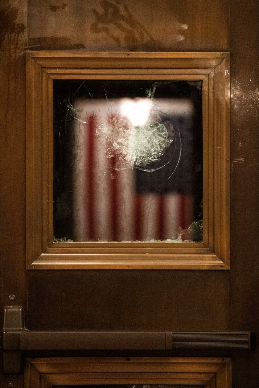 پرچم آمریکا در پنجره شکسته ساختمان کنگره آمریکا منعکس شده است 