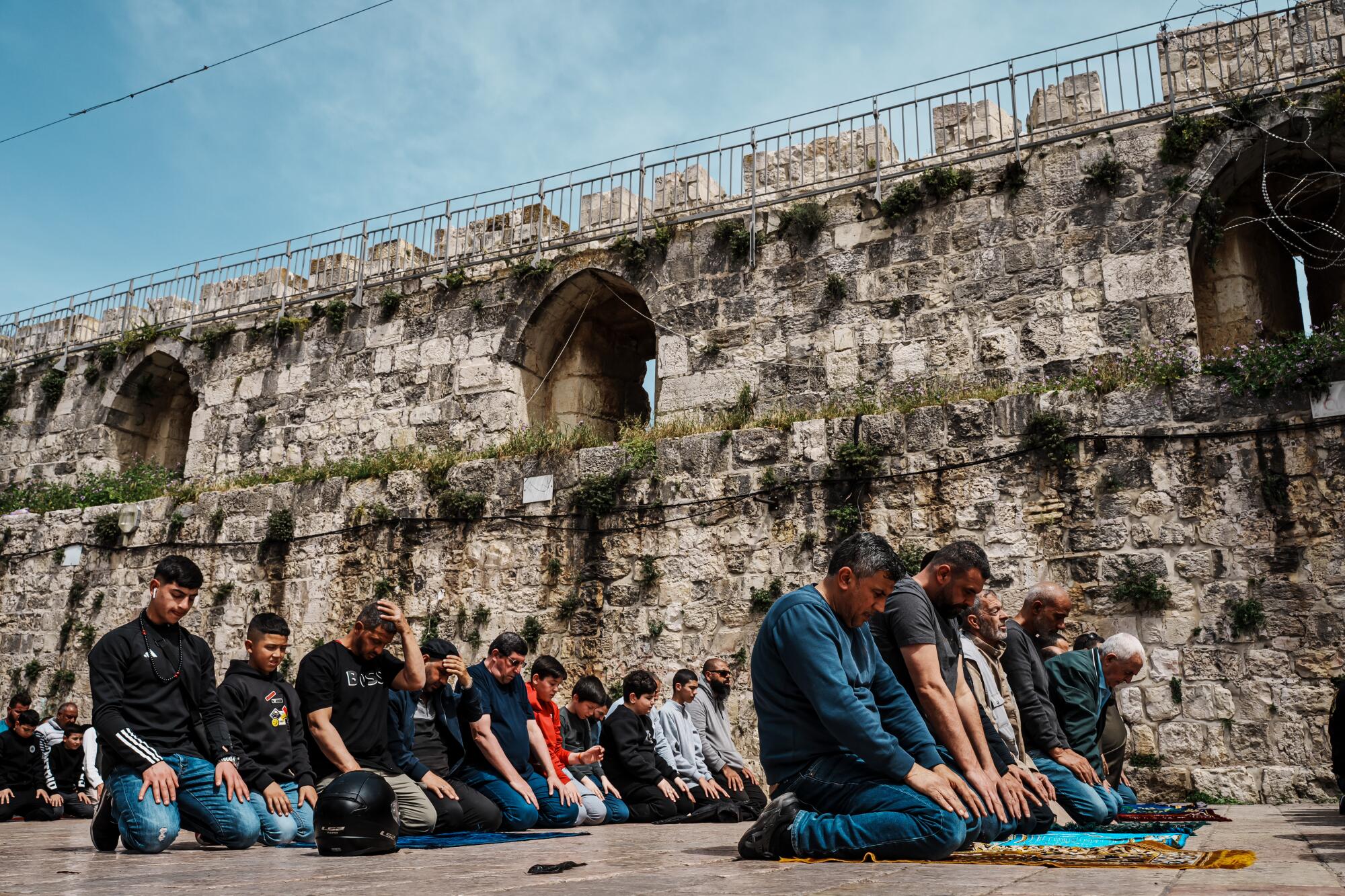 An overflow of worshipers perform Dhuhr afternoon prayers outside 