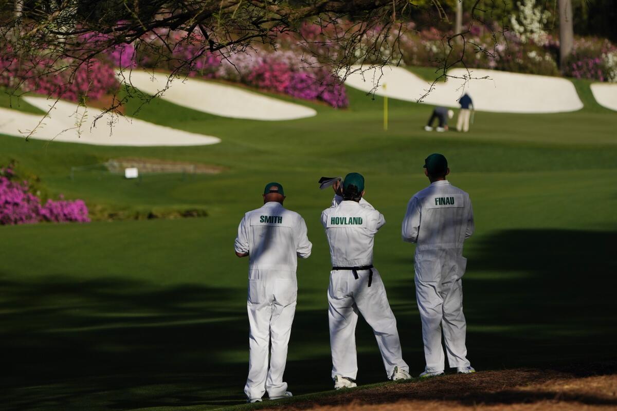 Masters' caddies examine the 13th hole at Augusta National.