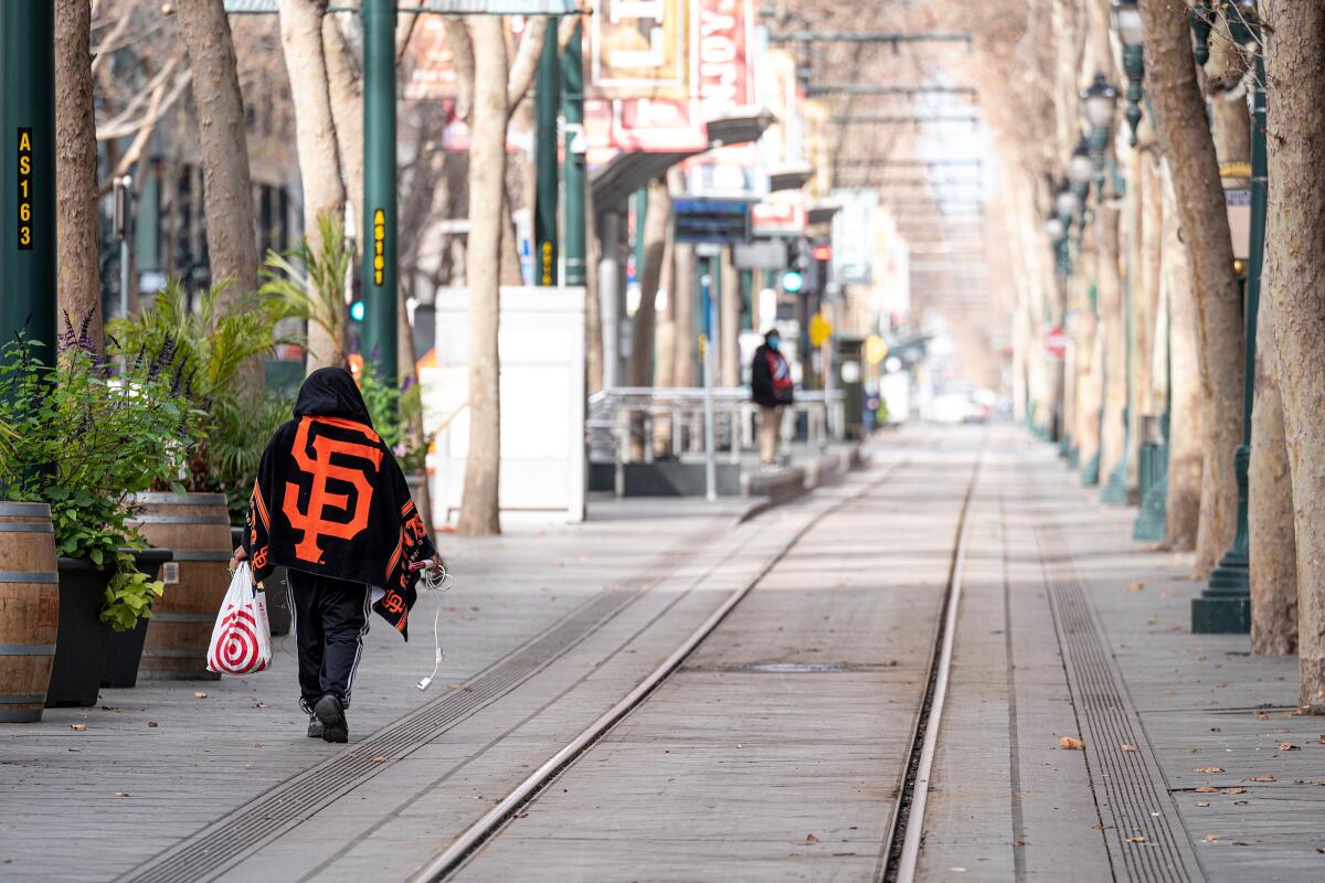 A person walks along the light rail tracks in downtown in San Jose.