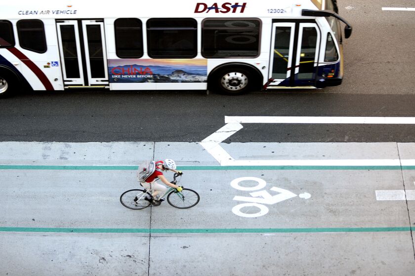 A bus passes a cyclist using a bike lane in downtown Los Angeles on Aug. 11, 2015.