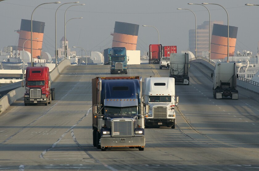 Trucks hauling cargo containers drive through the Port of Long Beach near Pier T.