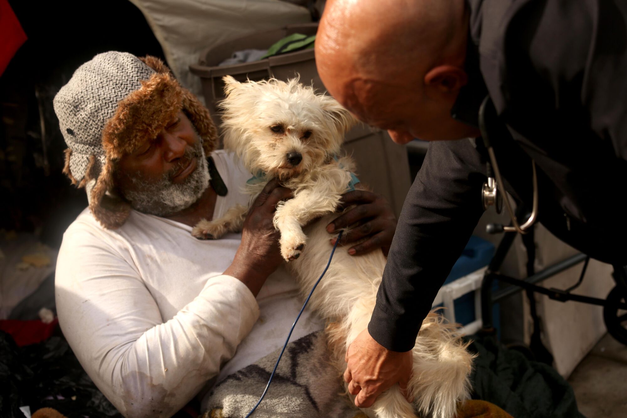 A bearded man in a fur cap holds a dog on his lap.