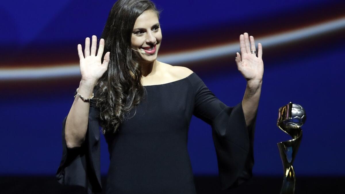 Carli Lloyd of the United States stands by the Women's World Cup trophy during the France 2019 draw in Paris.