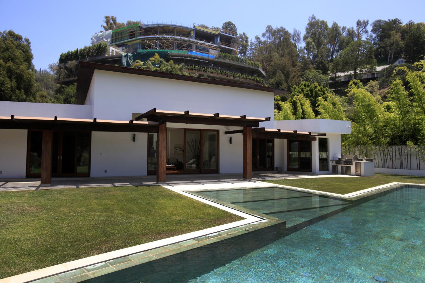 A Balinese-inspired contemporary home owned by Joseph Horacek III is overshadowed by a mammoth house under construction above it. City officials have pulled the construction permits. (Francine Orr, Los Angeles Times)