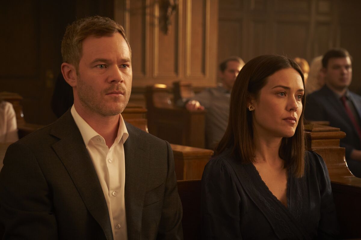 A man and a woman sit in a courtroom.