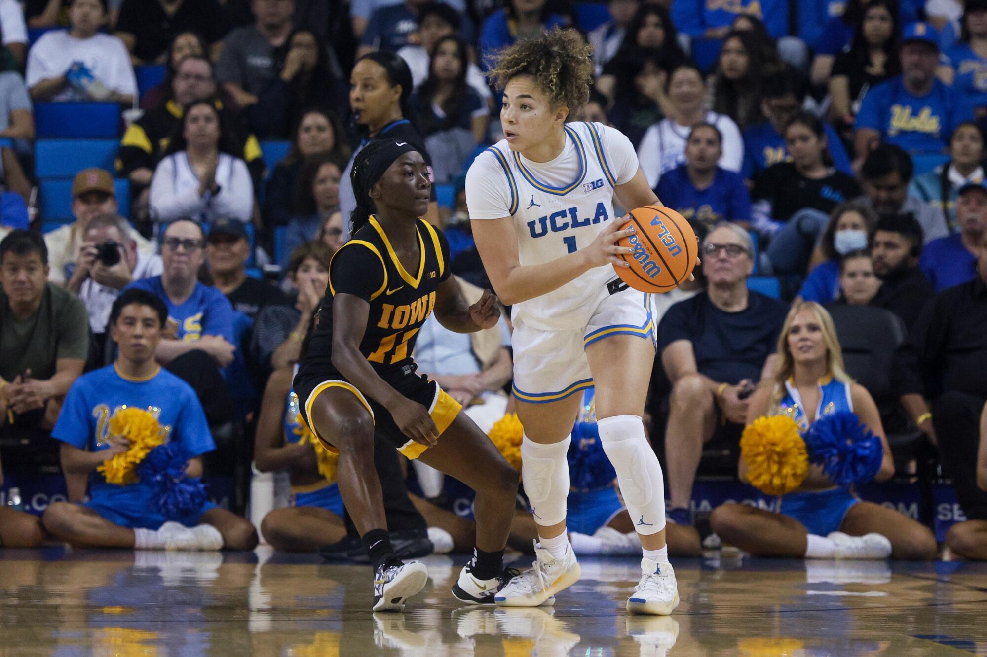 UCLA guardı Kiki Rice (sağda), Pazar gününün ilk yarısında Iowa guardı Chit-Chat Wright'ın önünde pas arıyor.