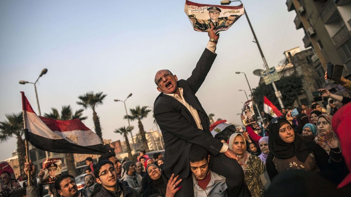 An Egyptian man holds a portrait of then-Defense Minister Gen. Abdel Fattah Sisi outside a polling station during the vote on a new constitution in 2014.