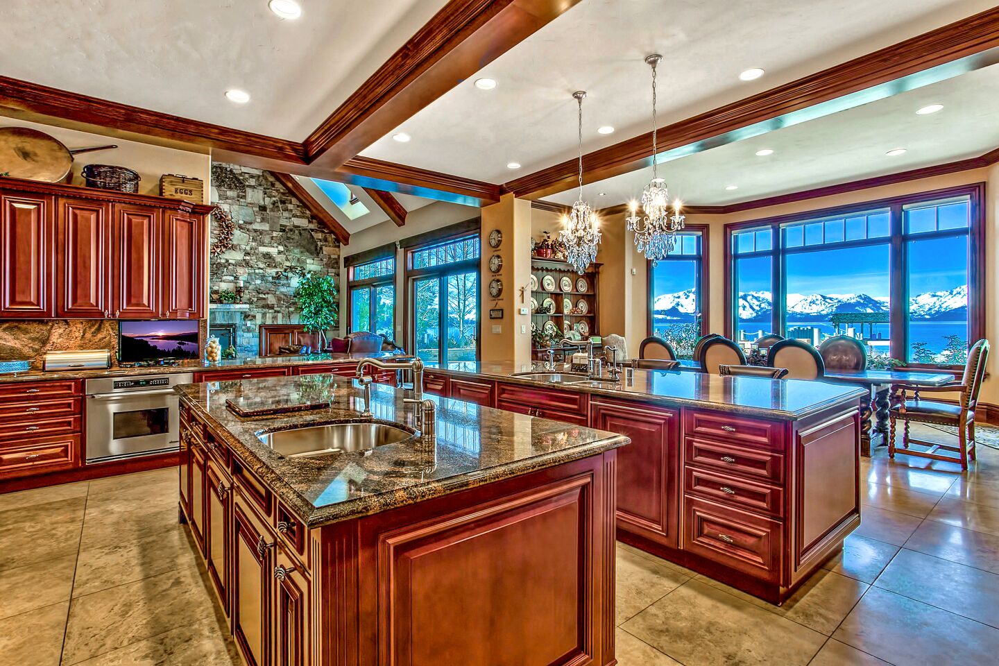 The home's kitchen and dining areas with dark wood cabinetry, granite countertops and picture windows with views of the lake