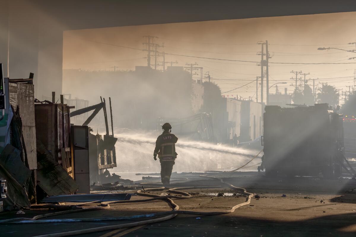 A firefighter is silhouetted under the smoky overpass.
