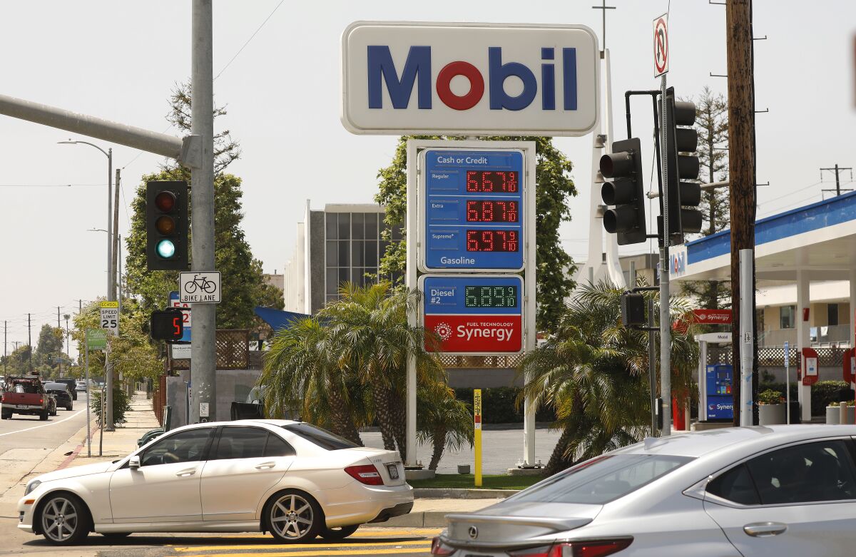 A Mobil gasoline station on a street corner with a sign for prices ranging from $6.67 to $6.97.
