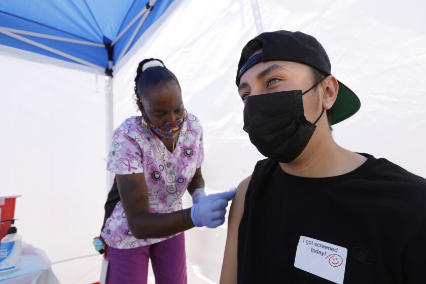 California postpones decision on relaxing face mask and
distancing rules for workers 4 Los Angeles, California—May 12, 2021—At the East Los Angeles Civic Center, St. John’s Well Child & Family Center runs a vaccine clinic. Tanya Mitchell, a certified medical assistant, left, administers his a vaccinate to Richard Ayala, age 18, on California on May 12, 2021. (Carolyn Cole / Los Angeles Times)