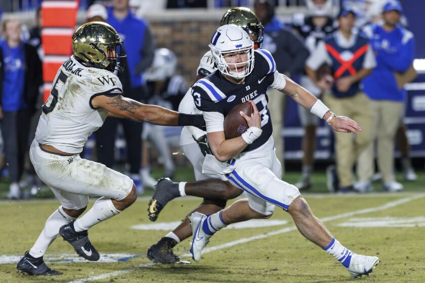 Duke's Riley Leonard (13) carries the ball past Wake Forest's Ryan Smenda, Jr. (5) during the second half of an NCAA college football game in Durham, N.C., Saturday, Nov. 26, 2022. (AP Photo/Ben McKeown)